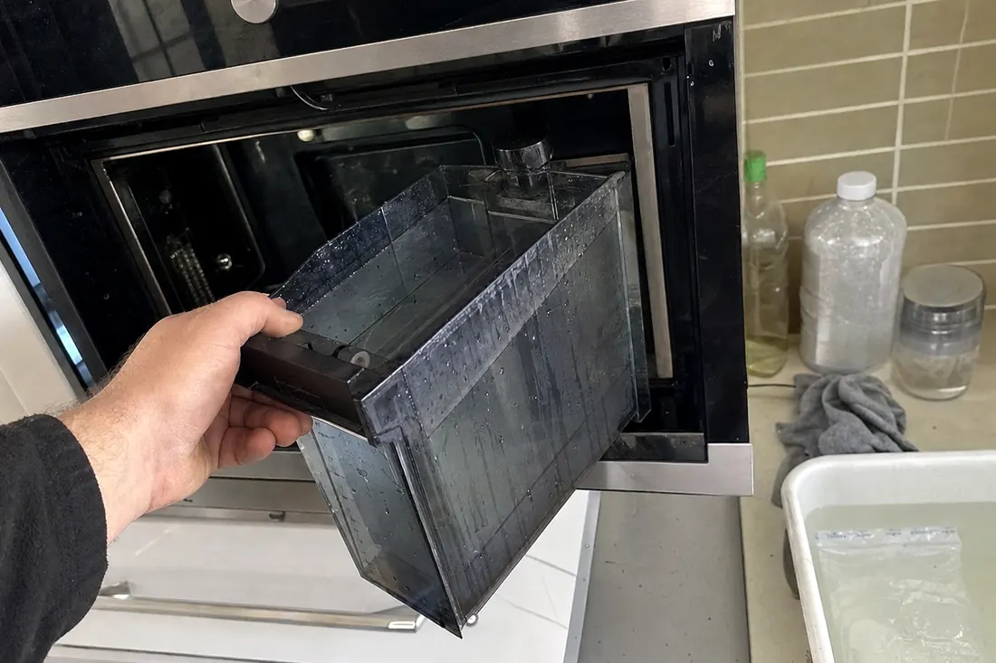 Hands lifting the water reservoir out of a built-in steam oven, the oven cavity in frame - What customers said afterwards